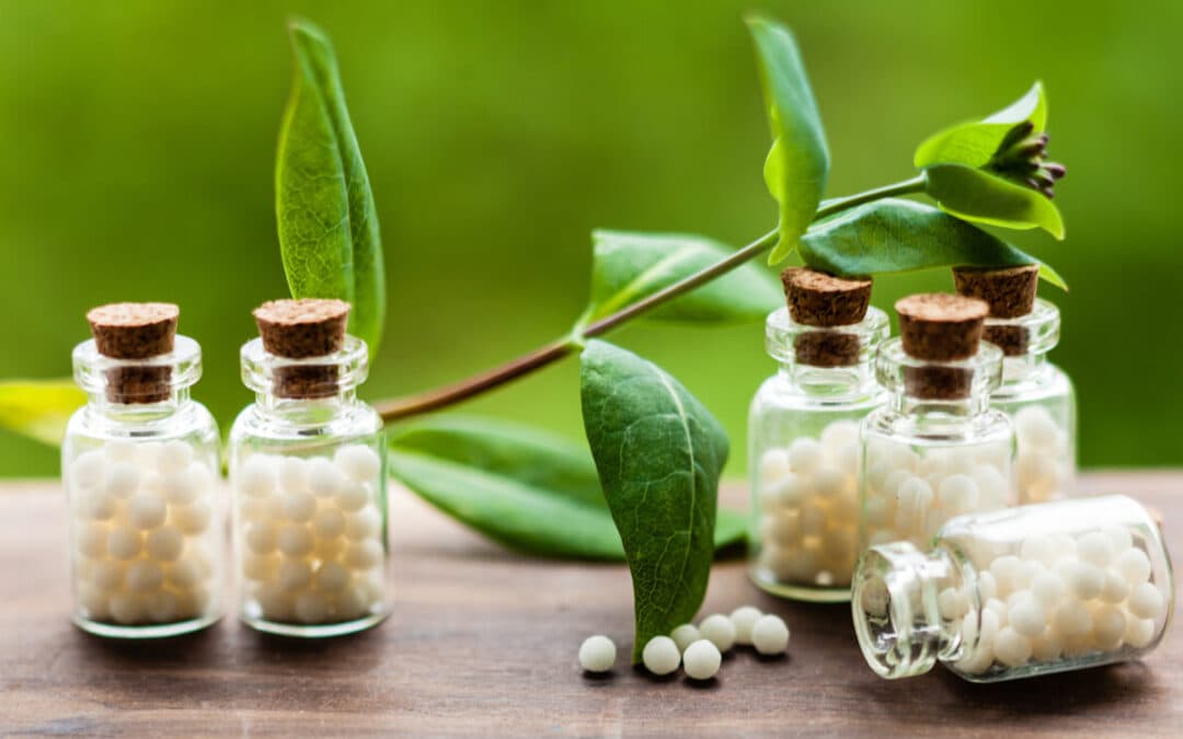 Homeopathic medicine bottles beside fresh green leaves